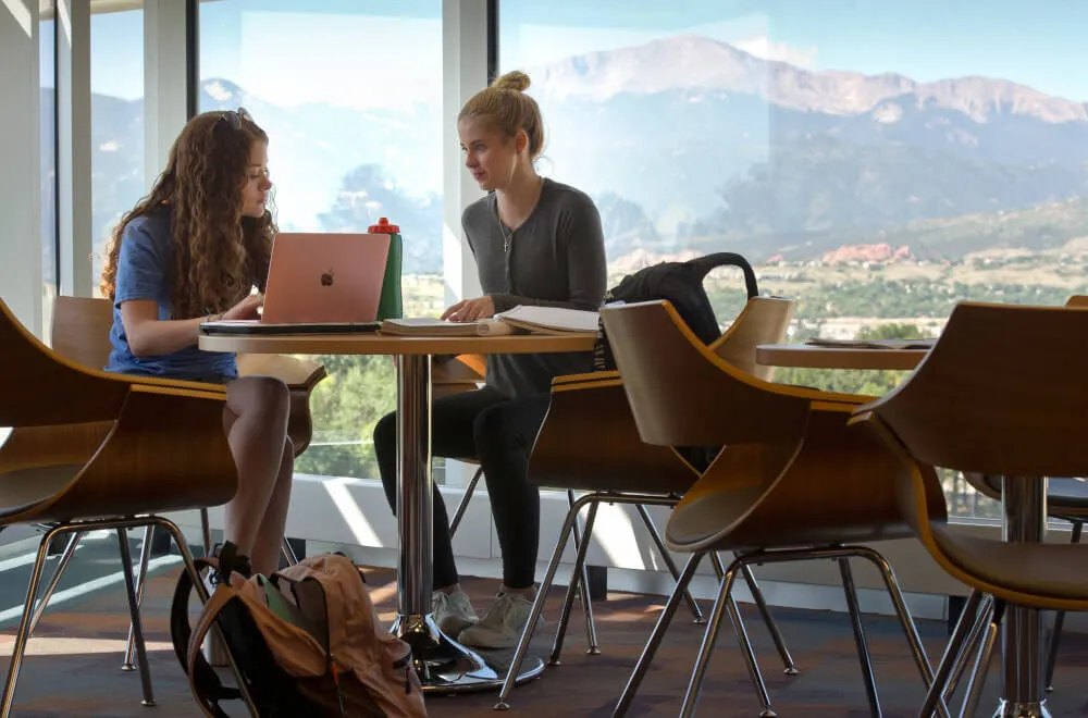 Students discussing something with Pikes Peak in the background.